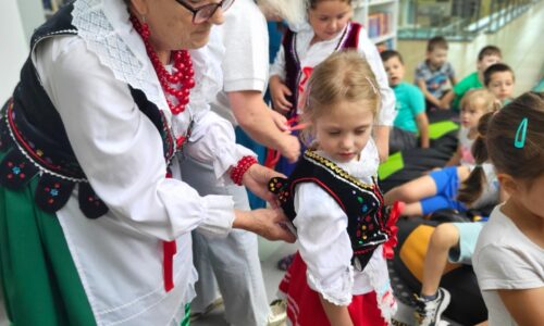 starsza kobieta ubiera dziecko w strój ludowy