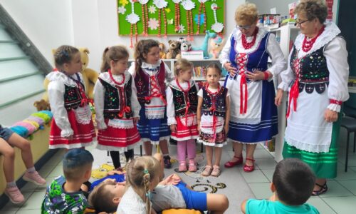 dzieci i starsze kobiety w strojach ludowych pozują do zdjęcia